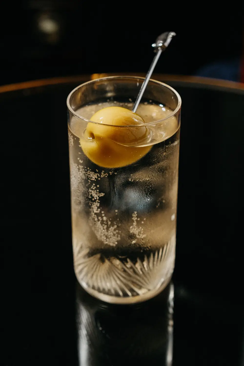 Vermut blanco con tónica y una oliva pinchada en un palillo